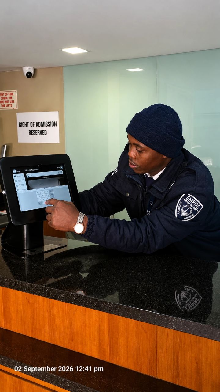 Empire officer using a visitor sign-in tablet at a building reception desk